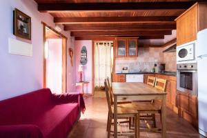 cocina con mesa de madera y sofá rojo en Home2Book Stunning Rustic House El Pinar & WiFi, en El Pinar de El Hierro