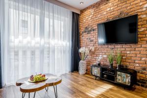 - un salon avec un mur en briques et une télévision dans l'établissement Apartament Merkury z parkingiem, à Toruń