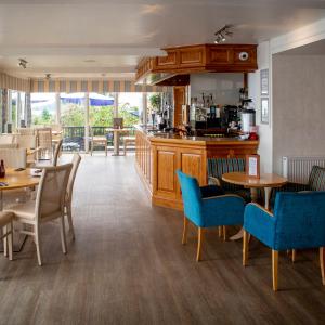 a restaurant with tables and chairs and a kitchen at The Hannafore Point Hotel in Looe