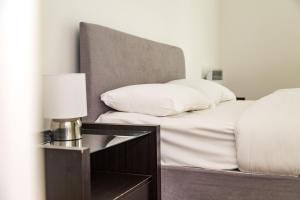 a bed with white pillows and a table with a lamp at Serviced Apartment In Liverpool City Centre - Free Parking - Balcony - by Happy Days in Liverpool