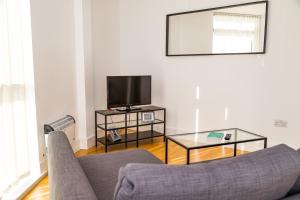 a living room with a couch and a tv at Serviced Apartment In Liverpool City Centre - Free Parking - Balcony - by Happy Days in Liverpool