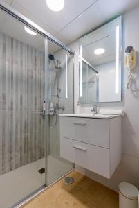 La salle de bains est pourvue d'une douche, d'un lavabo et d'un miroir. dans l'établissement Bamberg Giralda Skyview by Valcambre, à Séville
