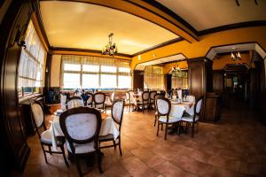 Hotel Trei Brazi في بايل أولانستي: غرفة طعام مع طاولات وكراسي ونوافذ