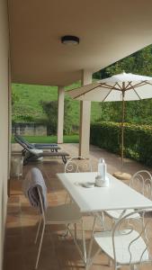 a patio with a table and an umbrella and chairs at LE SETTE VIE HOLIDAY HOMES in Monforte dʼAlba