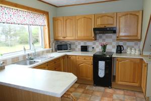 a kitchen with wooden cabinets and a black dishwasher at Druimard, Lower Barvas, Isle of Lewis in Barvas