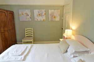 a bedroom with a white bed and three pictures on the wall at Gardeners Cottage in Chesthill