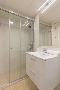 een witte badkamer met een wastafel en een douche bij Bamberg Central Suite by Valcambre in Sevilla