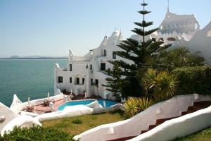 a large white house with a swimming pool next to the water at Club Hotel Casapueblo in Punta del Este