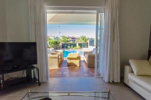 sala de estar con TV y balcón con piscina en Villa Meloneras, en Meloneras