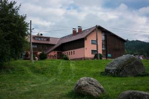 un grande edificio in un campo con delle rocce di fronte di Hacienda ČERT Kořenov a Kořenov