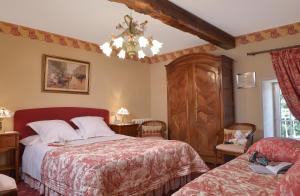 a bedroom with two beds and a chandelier at Hostellerie de la Motte jean in Saint-Coulomb