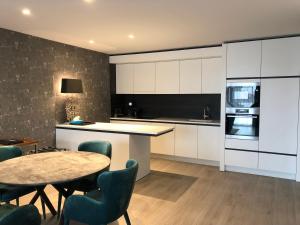 a kitchen with white cabinets and a table and chairs at Acropolis - Luxury Appartments I Hotelservice and FREE parking in Middelkerke