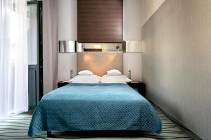 1 dormitorio con 1 cama con manta azul en Plaza Boutique Hotel en Cracovia