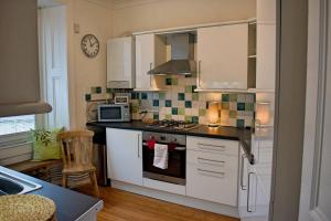 a kitchen with white cabinets and a stove top oven at The Old Pickle House in Kelso