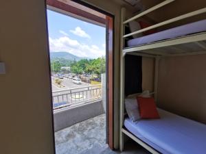 um quarto com uma varanda com uma cama e uma janela em Lodge88 ( l l ) em Ranau