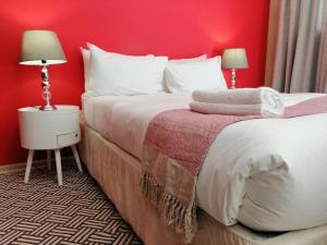 1 dormitorio con 2 camas y pared roja en The Bridgeview, en Johannesburgo