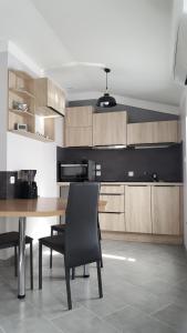 a kitchen with a wooden table and black chairs at Gîte du Domaine de la Forge in Boncourt-sur-Meuse