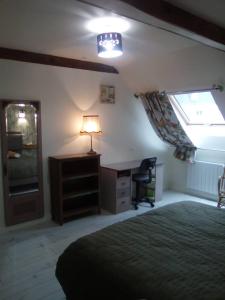 1 dormitorio con cama, escritorio y lámpara en CHAMBRES D'HOTES, en Loudéac
