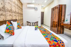 1 dormitorio con cama blanca y almohadas coloridas en FabHotel Elysian Grand Lucknow Airport, en Lucknow