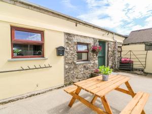 a wooden picnic table in front of a cottage at The Old Cows House in Helston