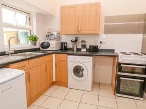a kitchen with a washing machine and a sink at The Old Cows House in Helston