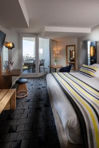 ein Hotelzimmer mit einem großen Bett und einem Balkon in der Unterkunft Thalazur Port-Camargue - Hotel & Spa in Le Grau-du-Roi