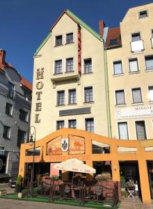 um grande edifício com um guarda-chuva em frente em Hotel Restauracja Podzamcze em Szczecin