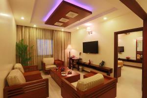 een woonkamer met een bank en een tv bij Hotel Abhimaani Vasathi, Rajajinagar in Bangalore