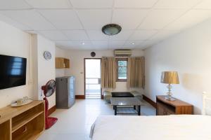 a room with a bed and a tv and a couch at Chiang Mai Mansion in Chiang Mai