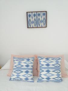 uma cama com duas almofadas e uma fotografia na parede em PINK LEMON apartments em Córdoba