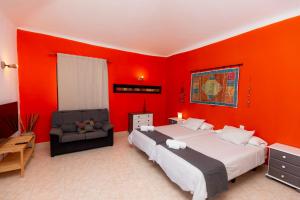 1 dormitorio con paredes rojas, 1 cama y 1 silla en Villas Reina, en Costa Teguise