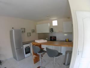 eine Küche mit einem Kühlschrank sowie einem Tisch und Stühlen in der Unterkunft Au bonheur des Anes - Gîte Topaze in Le Quesnoy-en-Santerre
