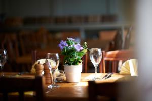 una mesa con copas de vino y una maceta en ella en The Bugle Inn Twyford en Winchester