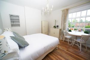 1 dormitorio con cama blanca, mesa y ventana en The Bugle Inn Twyford, en Winchester