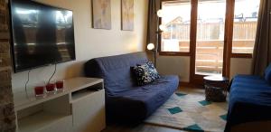 een woonkamer met een blauwe bank en een flatscreen-tv bij L'Ours Blanc in Huez