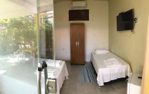 サン・ミゲル・ド・ゴストーゾにあるPousada Cruzeiro do Sulの小さなお部屋で、ベッド1台、ガラスのスライドドアが備わります。