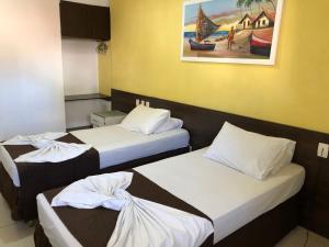 three beds in a room with a painting on the wall at Hotel Des Basques in Maceió