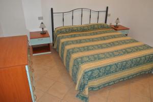 ein Schlafzimmer mit einem Bett mit zwei Nachttischen und einer Kommode in der Unterkunft Case Vacanza Fenicotteri in San Teodoro