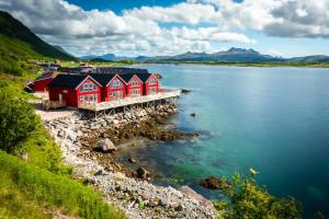 a row of red houses on the shore of a lake at Lofoten Rorbu Lodge in Offersøya