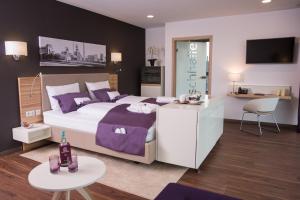 a bedroom with a large bed with purple pillows at Heiner's Parkhotel in Gelsenkirchen