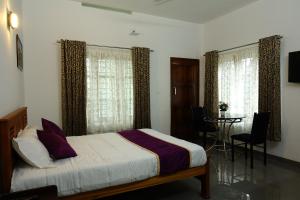 a bedroom with a bed and a table and windows at Rose Cottage in Munnar