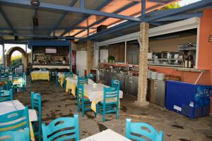 um restaurante com mesas e cadeiras azuis e uma cozinha em Aithrio Hotel em Niforeika