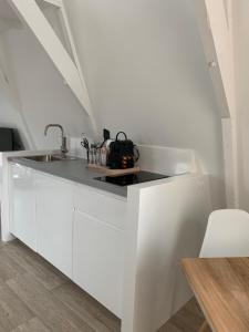 eine weiße Küche mit einer Spüle und einer Theke in der Unterkunft Payglop III in Alkmaar