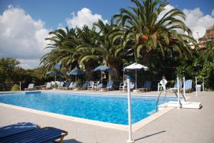 una piscina con sedie, ombrelloni e palme di Anna Studios a Pythagóreion