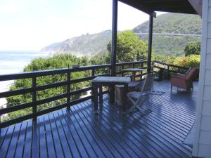 una terrazza in legno con tavolo e sedie su una casa di Wilderness Beach House Backpackers Lodge a Wilderness