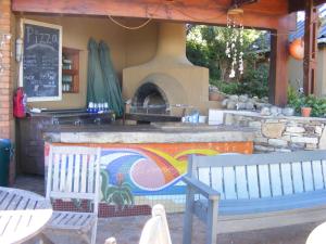 un patio con 2 bancos y un horno de pizza en Wilderness Beach House Backpackers Lodge, en Wilderness