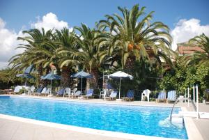 una piscina con palme, sedie e ombrelloni di Anna Studios a Pythagóreion