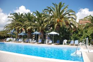 a pool with palm trees and chairs and umbrellas at Anna Studios in Pythagoreio