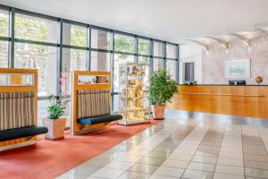a lobby with chairs and plants in a building at IntercityHotel Erfurt in Erfurt