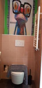 a bathroom with a toilet and a painting on the wall at JaBaKi Green Studio in Hoofddorp